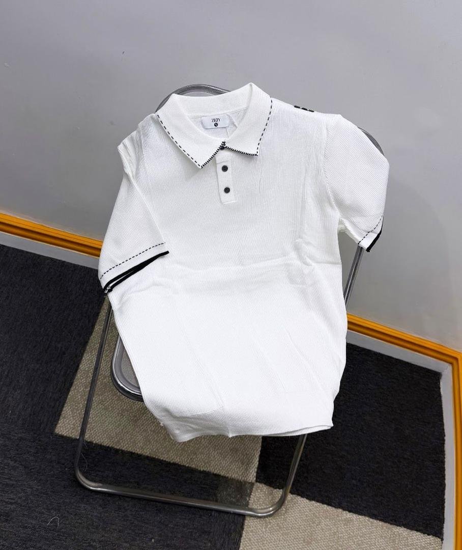 A luxurious white polo dress with contrasting stitching details, showcased on a chair against a neutral background, highlighting its sophisticated design and premium quality.