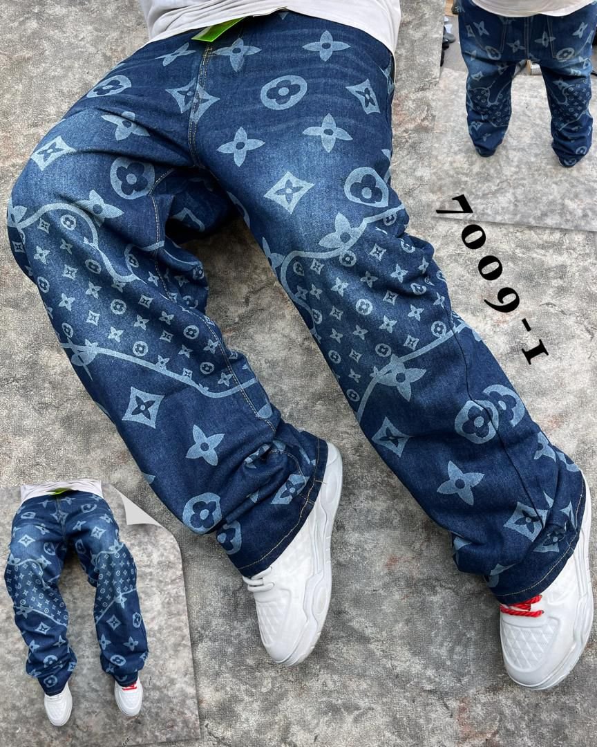 A pair of men's blue denim jeans with Louis Vuitton monogram pattern, laid on a gray concrete floor, showcasing the stylish and comfortable design.