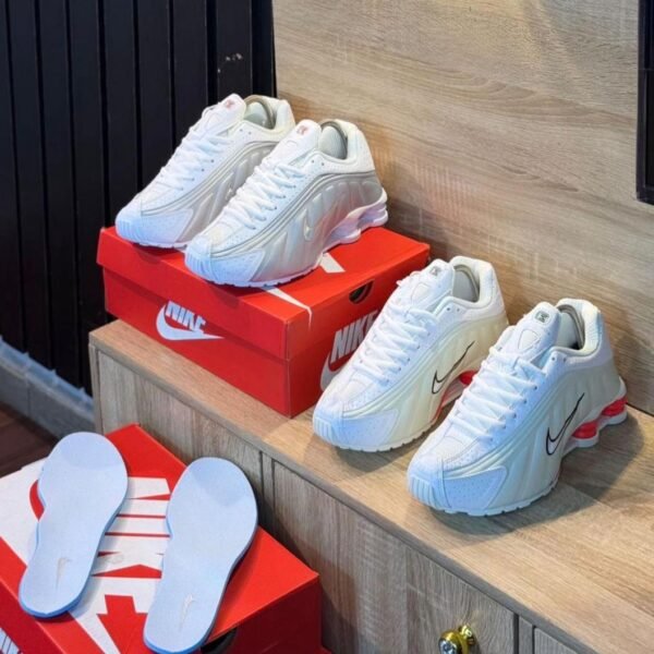 A pair of white Nike Air Max 270 React sneakers with red accents, showcasing Modern Luxury and Urban Edge style.