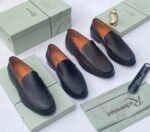 A pair of black woven leather loafers displayed on a shoe box, showcasing the intricate details and craftsmanship of the shoes.