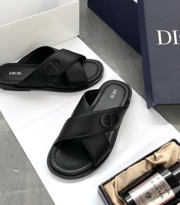 A pair of black leather Dior slides with white logo on a white background, showcasing Modern Luxury and Urban Edge style.