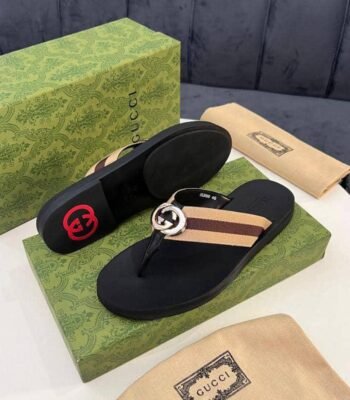 Gucci black slide sandals with interlocking GG buckle and striped strap, displayed on a green box with packaging.