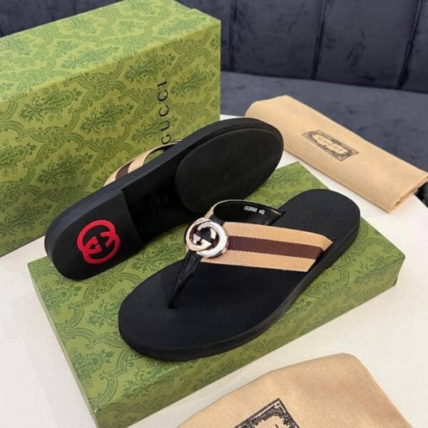 Gucci black slide sandals with interlocking GG buckle and striped strap, displayed on a green box with packaging.