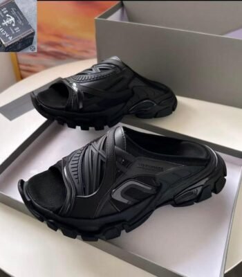 A pair of black Balenciaga rubber mules in a shoe box, showcasing the modern design and luxury quality of the shoes.