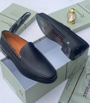 A pair of black woven leather loafers displayed on a shoe box, showcasing the intricate details and craftsmanship of the shoes.