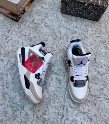 A pair of white, black, and grey Air Jordan 4 Retro sneakers on a marble surface, exuding luxury and style.