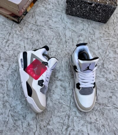 A pair of white, black, and grey Air Jordan 4 Retro sneakers on a marble surface, exuding luxury and style.