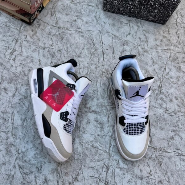 A pair of white, black, and grey Air Jordan 4 Retro sneakers on a marble surface, exuding luxury and style.