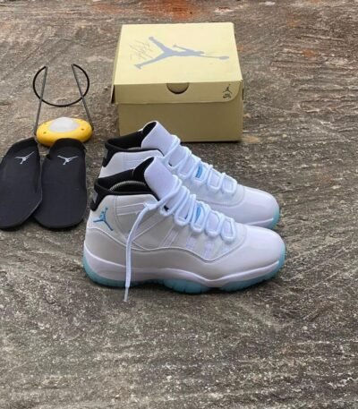A pair of white and blue Air Jordan 11 sneakers with black slides and a shoe box, embodying Modern Luxury and Urban Edge style.