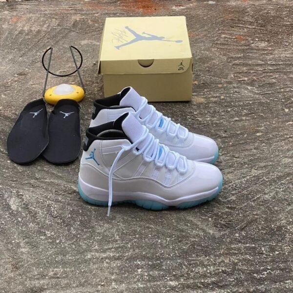 A pair of white and blue Air Jordan 11 sneakers with black slides and a shoe box, embodying Modern Luxury and Urban Edge style.