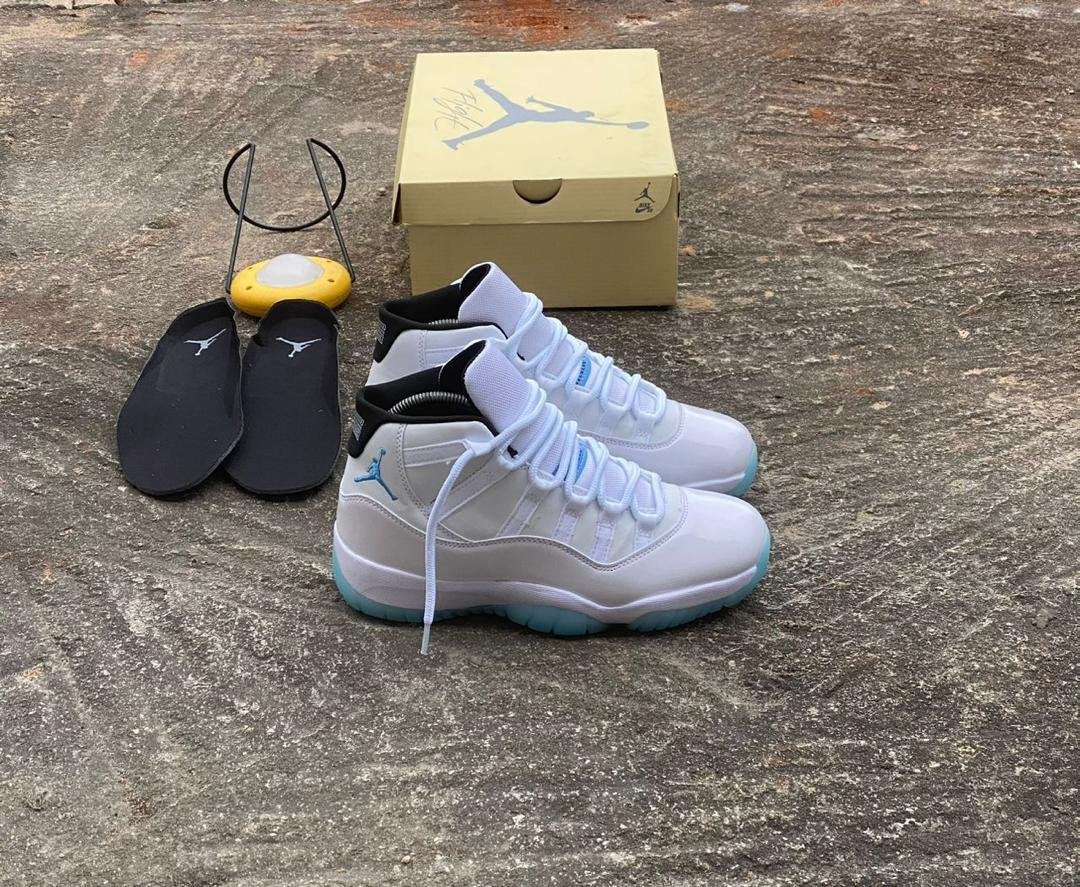 root A pair of white and blue Air Jordan 11 sneakers with black slides and a shoe box, embodying Modern Luxury and Urban Edge style.