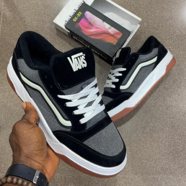 A pair of black and grey Vans skateboarding shoes with white laces and brown soles, showcasing Modern Luxury and Urban Edge.