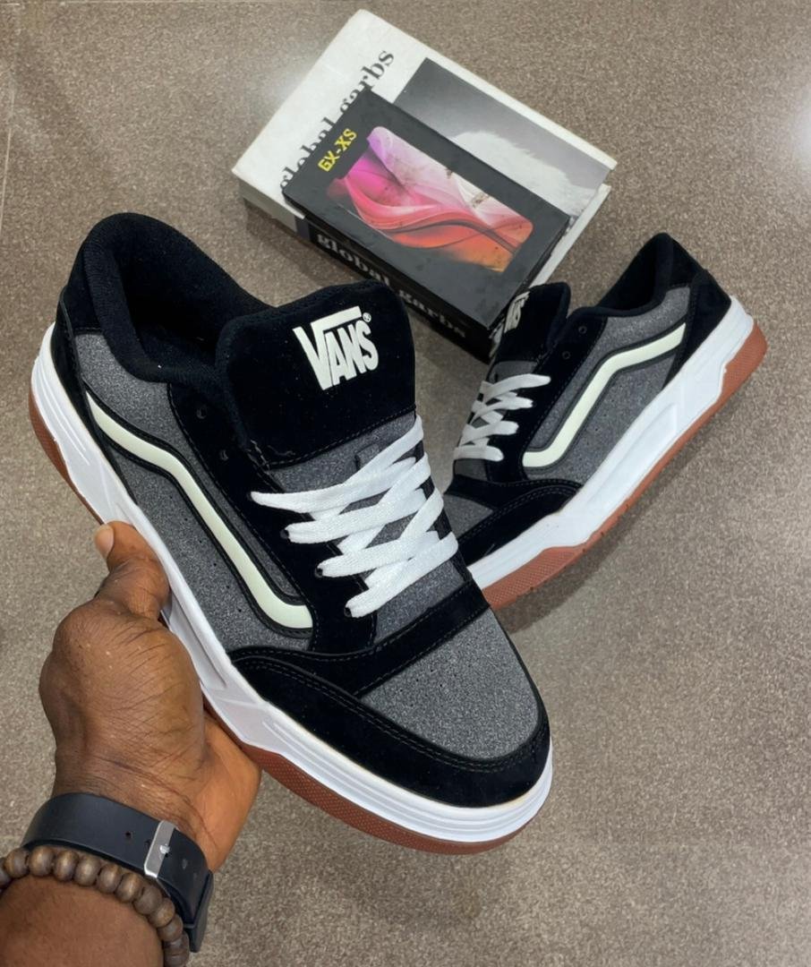root A pair of black and grey Vans skateboarding shoes with white laces and brown soles, showcasing Modern Luxury and Urban Edge.