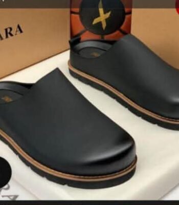A pair of black leather clog shoes with a brown sole, presented on a white box with a Zara box in the background, showcasing modern luxury and urban edge.
