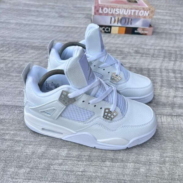 A pair of white leather sneakers with diamond accents, placed on a wooden surface with luxury brand boxes in the background.