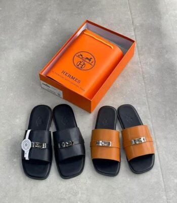 A stylish display of Hermes leather slide sandals in black and tan, accompanied by an orange Hermes box, showcasing the brand's iconic logo and commitment to luxury craftsmanship.