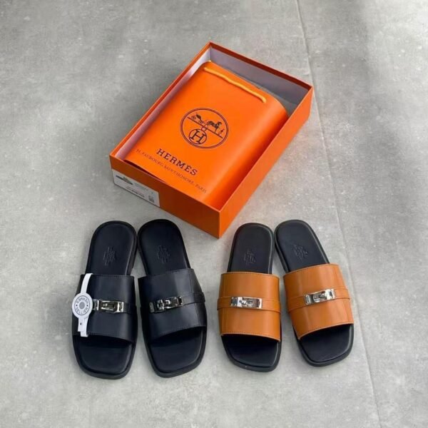 A stylish display of Hermes leather slide sandals in black and tan, accompanied by an orange Hermes box, showcasing the brand's iconic logo and commitment to luxury craftsmanship.