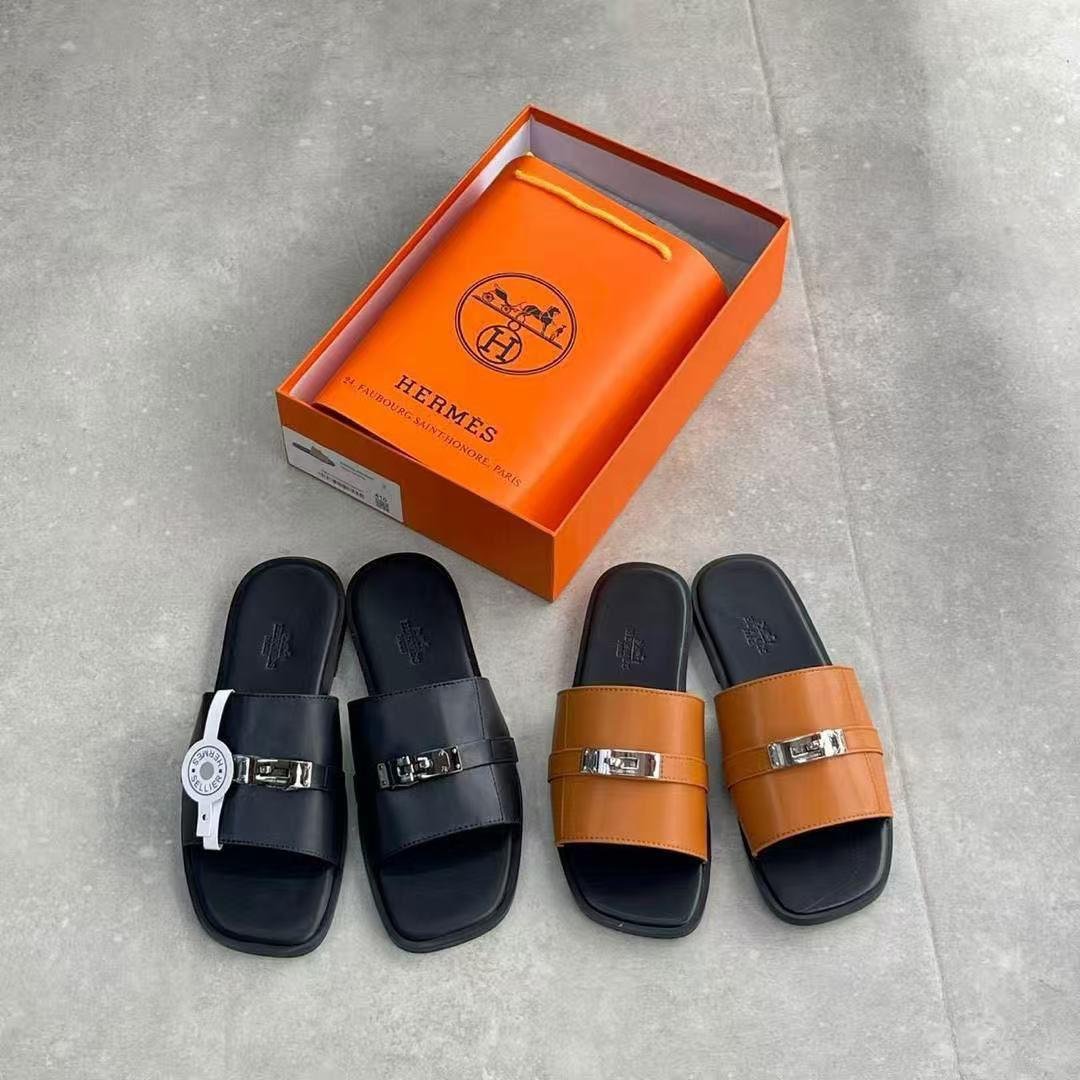 root A stylish display of Hermes leather slide sandals in black and tan, accompanied by an orange Hermes box, showcasing the brand's iconic logo and commitment to luxury craftsmanship.