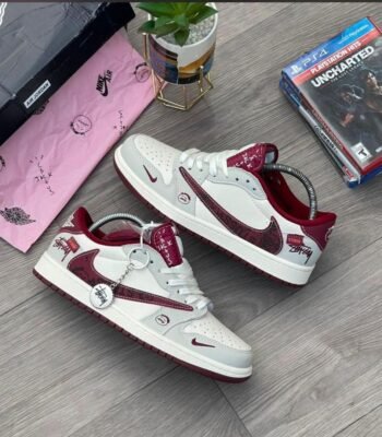 A pair of white and red Stussy x Nike Air Jordan 1 High 'Jack Black' sneakers on a wooden floor, exuding Modern Luxury and Urban Edge style.