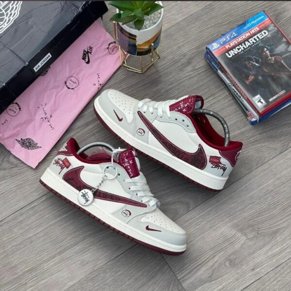 A pair of white and red Stussy x Nike Air Jordan 1 High 'Jack Black' sneakers on a wooden floor, exuding Modern Luxury and Urban Edge style.