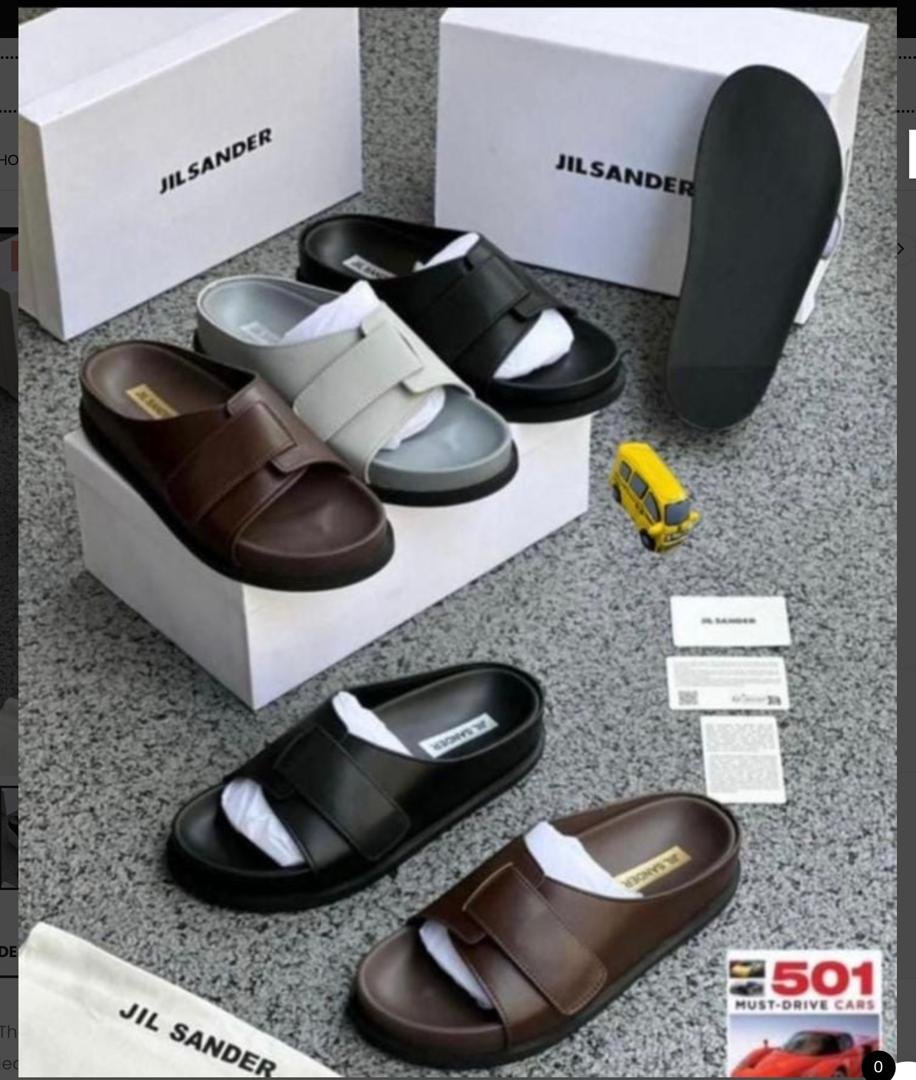 IMG-20260610-WA0018 A display of Jil Sander two-strap leather slides in brown and black, accompanied by their signature boxes and packaging, embodying Modern Luxury and Urban Edge.