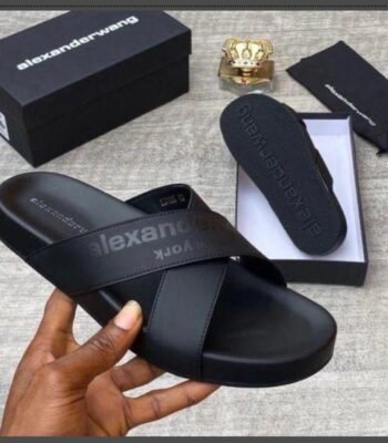 A pair of black leather slide sandals from Alexander Wang, displayed with its box and packaging, exuding Modern Luxury and Urban Edge style.