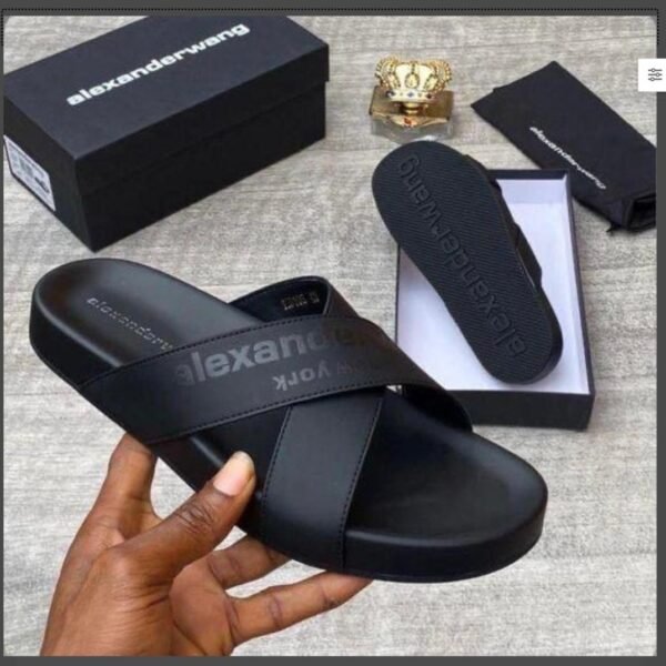 A pair of black leather slide sandals from Alexander Wang, displayed with its box and packaging, exuding Modern Luxury and Urban Edge style.