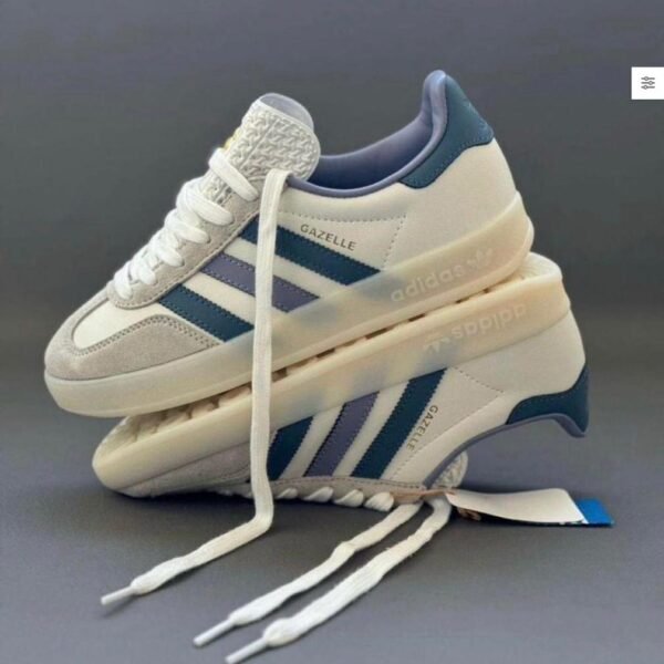 A pair of white and blue Adidas Gazelle Indoor sneakers stacked on top of each other, showcasing the shoe's sleek design and Urban Edge style.