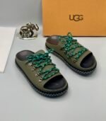 A pair of black leather UGG sandals with metal buckles and laces, exuding modern luxury and urban edge.