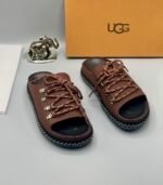 A pair of black leather UGG sandals with metal buckles and laces, exuding modern luxury and urban edge.