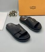 Grey UGG slide sandals with zigzag stitching and gold-tone buckle on a white surface, exuding Modern Luxury and Urban Edge.