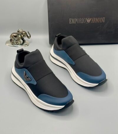 A pair of black and blue Emporio Armani sneakers with white soles, showcased with a silver elephant statue and a black Emporio Armani box in the background.