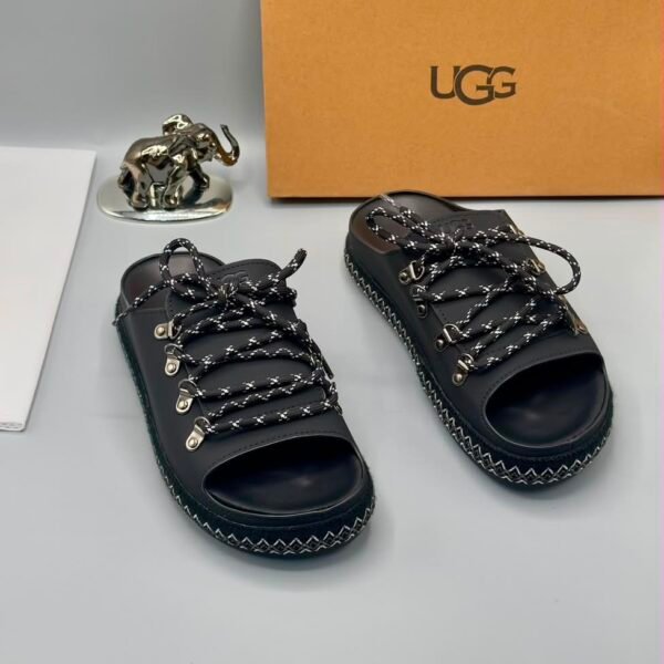 A pair of black leather UGG sandals with metal buckles and laces, exuding modern luxury and urban edge.
