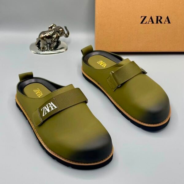 A pair of olive green strap shoes with a silver elephant statue and Zara box in the background, showcasing Modern Luxury and Urban Edge style.