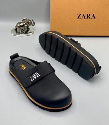 A pair of black leather clogs with gold accents and ZARA logo, showcasing modern luxury and urban edge.