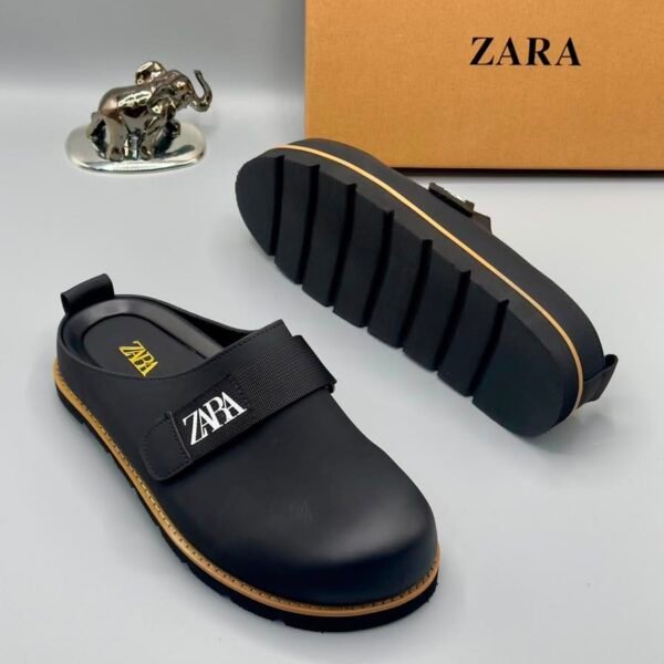 A pair of black leather clogs with gold accents and ZARA logo, showcasing modern luxury and urban edge.