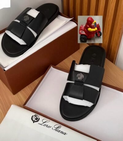 Luxurious black slides with two straps and a logo on top, placed in a brown shoe box with white tissue paper, embodying Modern Luxury and Urban Edge in Nigeria.
