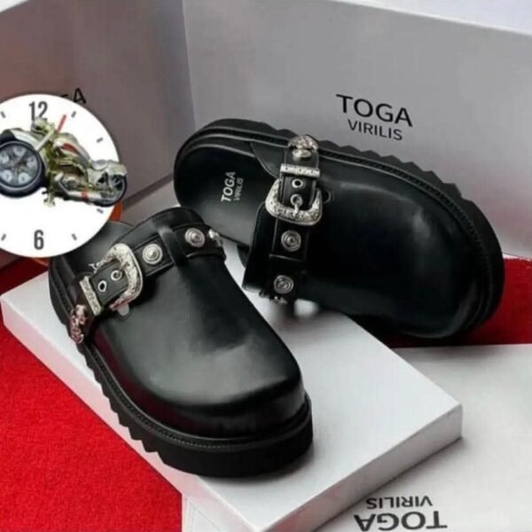 A pair of sleek black leather shoes with silver buckles, presented on a white box with the brand name 'TOGA VIRILIS' and a red carpet background, embodying Modern Luxury and Urban Edge in Nigeria.