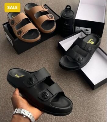 Modern luxury sandals in sleek black and tan colors, displayed with their boxes and a water bottle, embodying urban edge and timeless quality.