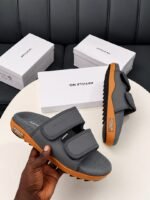 Modern luxury grey and orange sandals with white shoe boxes on a table, embodying urban edge and timeless quality.