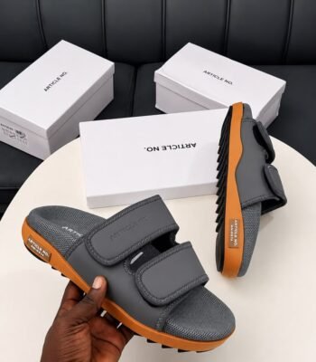 Modern luxury grey and orange sandals with white shoe boxes on a table, embodying urban edge and timeless quality.