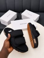 Modern luxury grey and orange sandals with white shoe boxes on a table, embodying urban edge and timeless quality.
