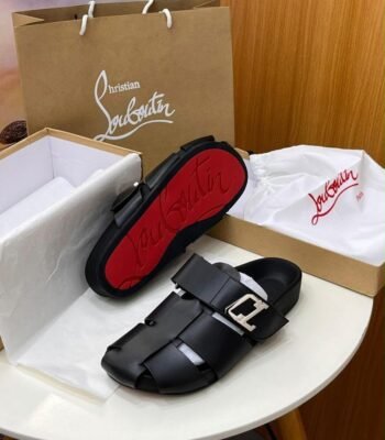 Christian Louboutin black leather sandal with red sole, presented in a luxury setting with box and bag.