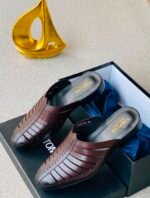 A pair of luxurious brown leather shoes in a box with a golden decorative item