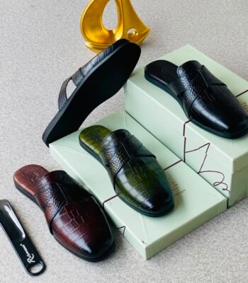 High-quality crocodile skin loafers in black, green and brown, displayed with shoe boxes and a shoe horn.
