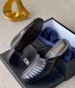 A pair of luxurious brown leather shoes in a box with a golden decorative item