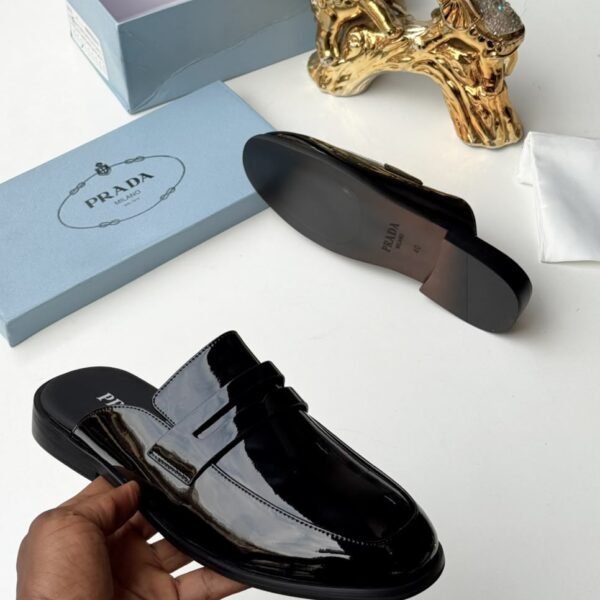 A sleek black Prada half shoes with a glossy finish, presented with its box and packaging, exuding modern luxury and urban edge.