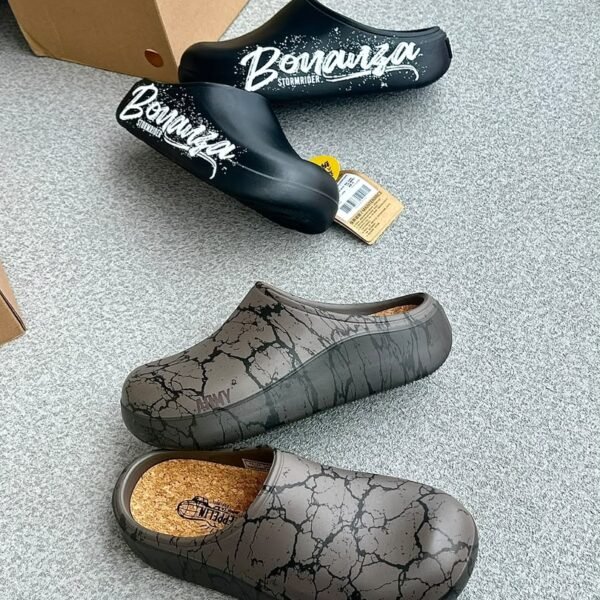 A pair of black clogs with white Bonanza Storm Rider branding and a pair of grey clogs with a cracked pattern, showcasing modern luxury footwear.
