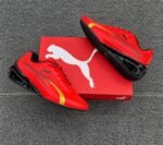 A pair of vibrant red Puma sneakers with gold and black accents, exuding Modern Luxury and Urban Edge, placed elegantly on a wooden floor next to their box.
