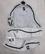 A luxurious black tracksuit with grey stripes and Nike logo, laid out on a grey surface.
